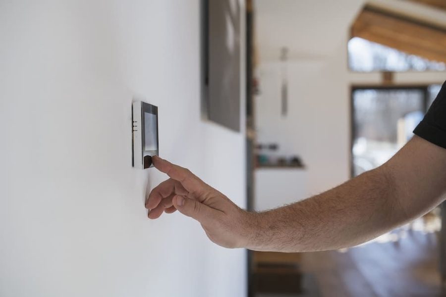 A homeowner adjusting their thermostat in their home